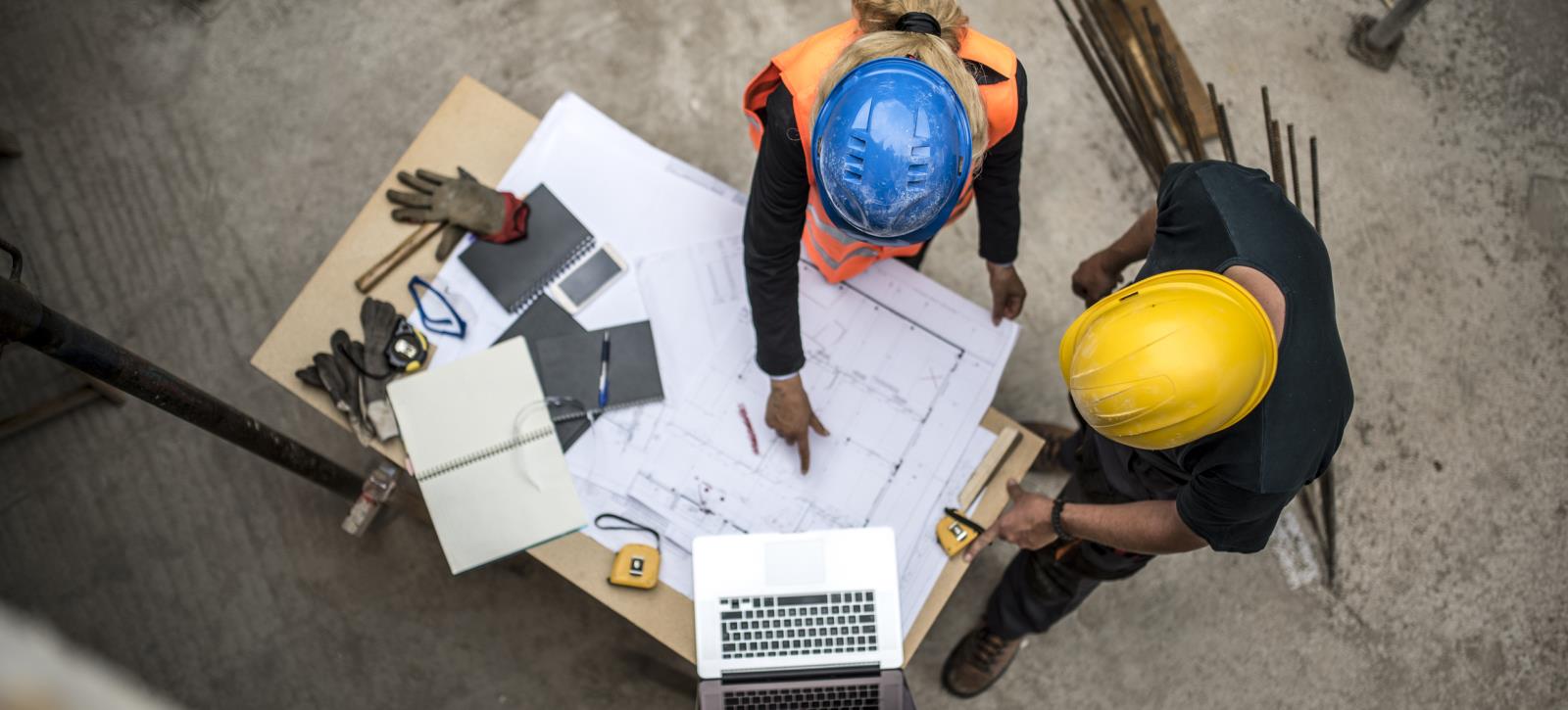 Birds eye view image of two men in hard hats reviewing site plan