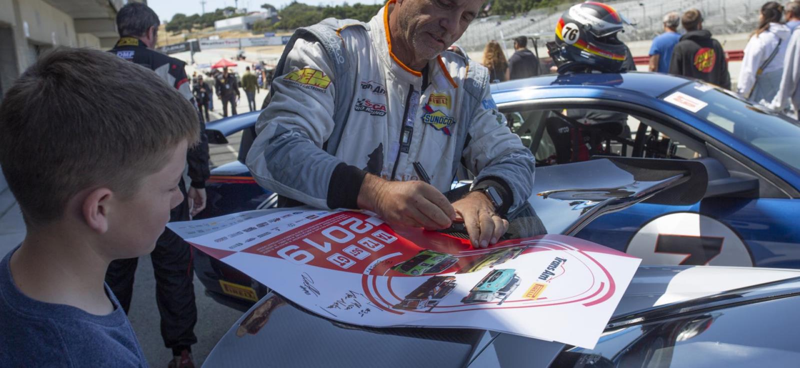 Photo of racer signing poster for adolescent