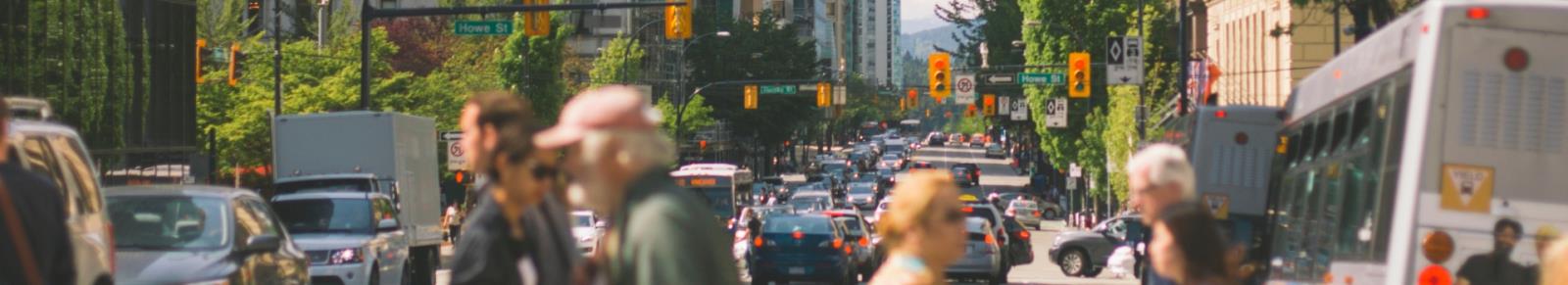 Panorama image of people crossing a busy city street