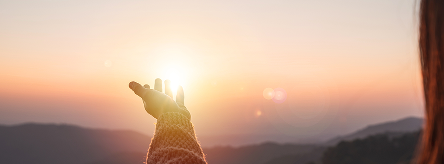 panoramic photo of a person reaching hand out towards the sun