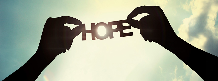 photo of two silhouetted hands holding a cut out of the words hope