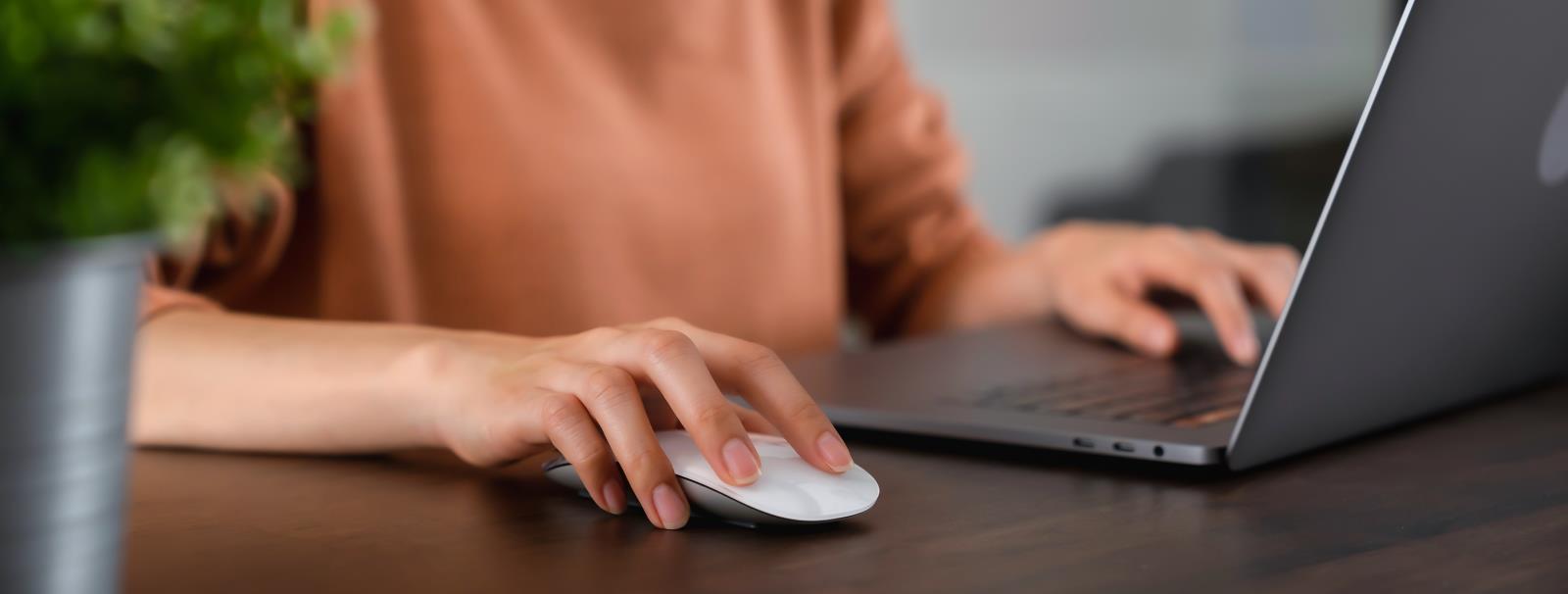 photo of close-up of hand pressing the button computer mouse and using laptop on table